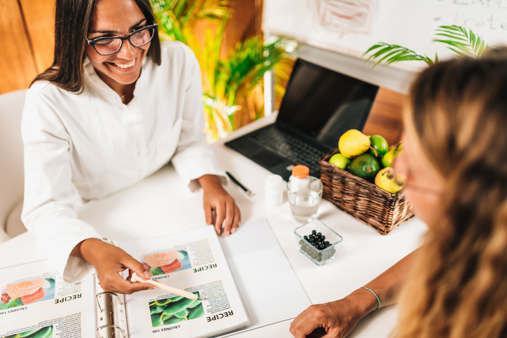 clinical dietitian pointing at data on desk to her patient