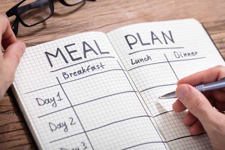 writing out a meal plan in a notebook
